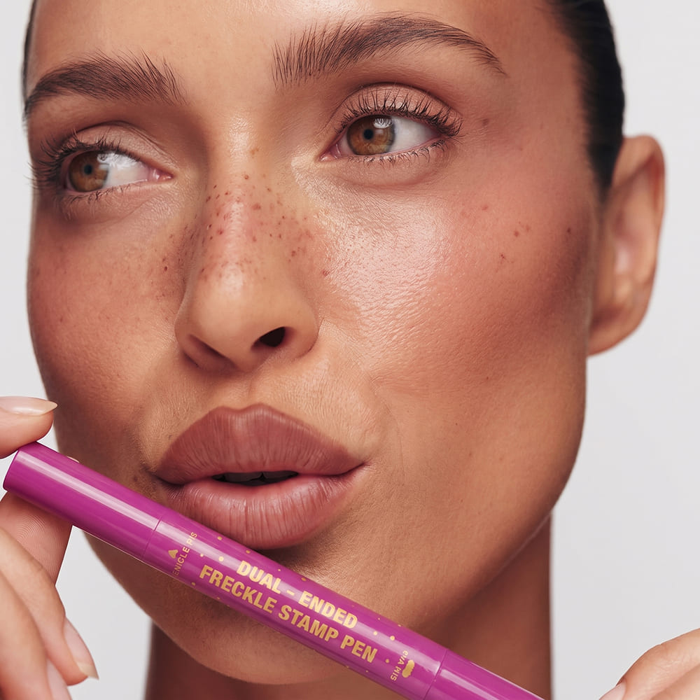 Woman holding a purple freckle stamp pen with a plain background