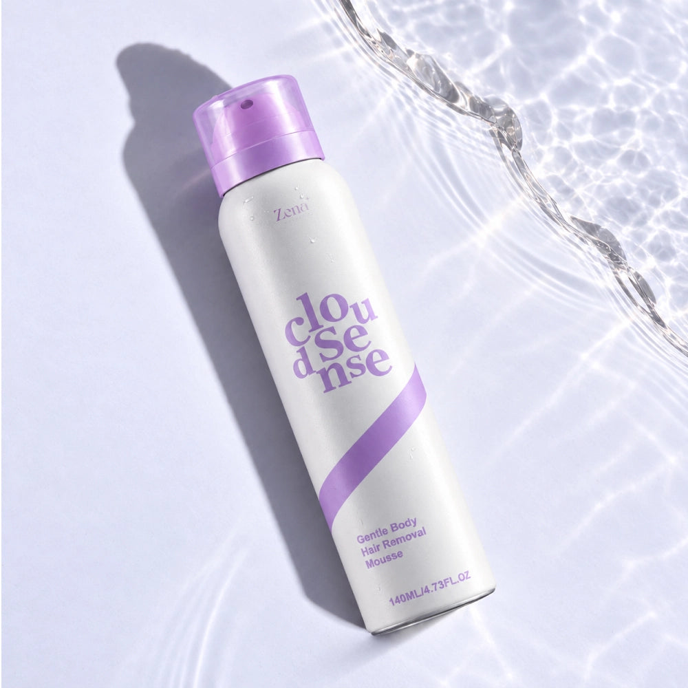 A can of Zena Cloud Sense Gentle Body Hair Remover mousse, featuring a white body and a lavender purple cap and stripe, set against a background of rippling water with light reflections.
