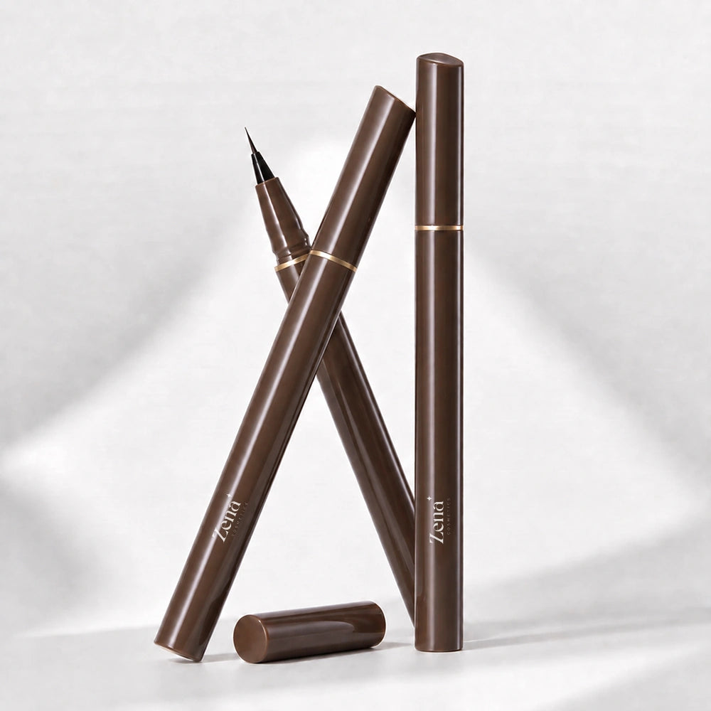 Three brown cosmetic pens with gold accents arranged in a studio setup on a light gray background. One pen is uncapped with its cap lying beside it, and the brand name 'Zena' is visible on the barrels.